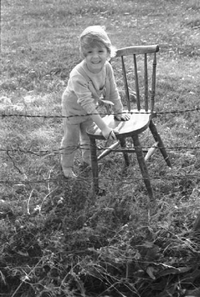 Svezia, öland - Laudie Nocera bambina in un campo che gioca con una sedia di legno