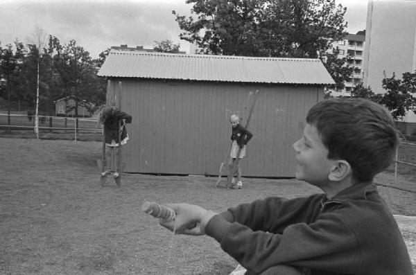Svezia - Bambino al parco giochi - Sullo sfondo bambini sui trampoli