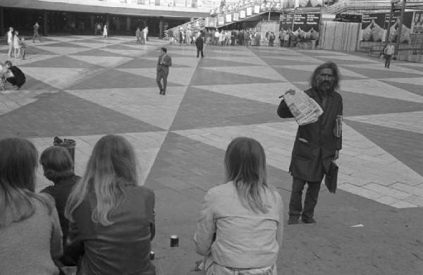 Svezia, Stoccolma - Mendicante fra la gente seduta sui gradini di un'isola pedonale - Entrata della metropolitana T-Centralen