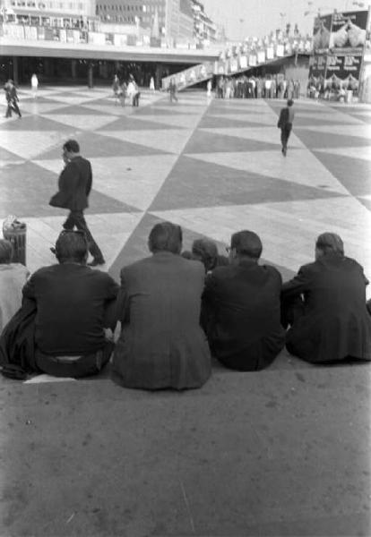 Svezia, Stoccolma - T-Centralen - Gruppo di giovani seduti di spalle sui gradini di una piazza pedonale