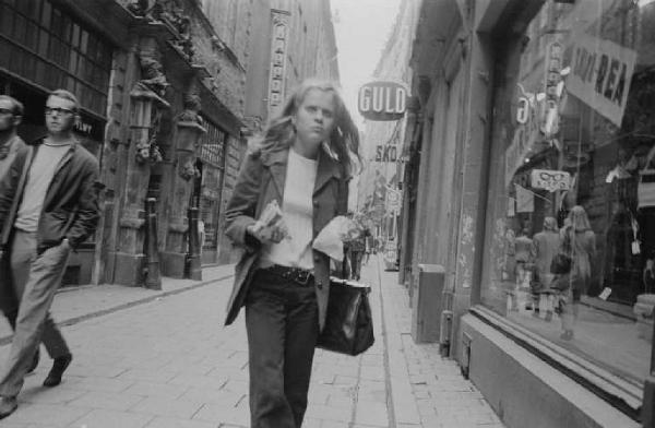 Svezia - Stoccolma - Giovane donna passeggia per una strada pedonale con negozi