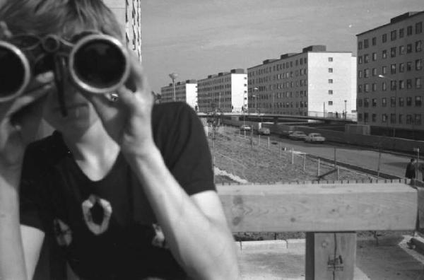 Skarholmen - Stoccolma - Donna con binocolo - Palazzine sullo sfondo