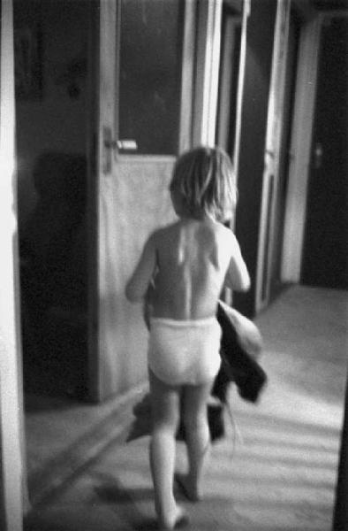 Bambina di spalle che cammina nel corridoio di casa