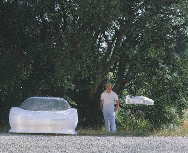 Autovettura sportiva - adulto posa di fianco al veicolo coperto da un telo bianco