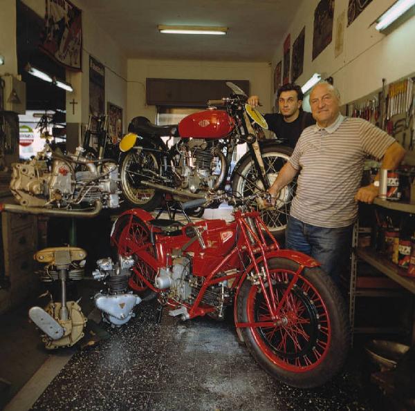 Officina di moto d'epoca - i titolari in posa accanto ad alcune motociclette