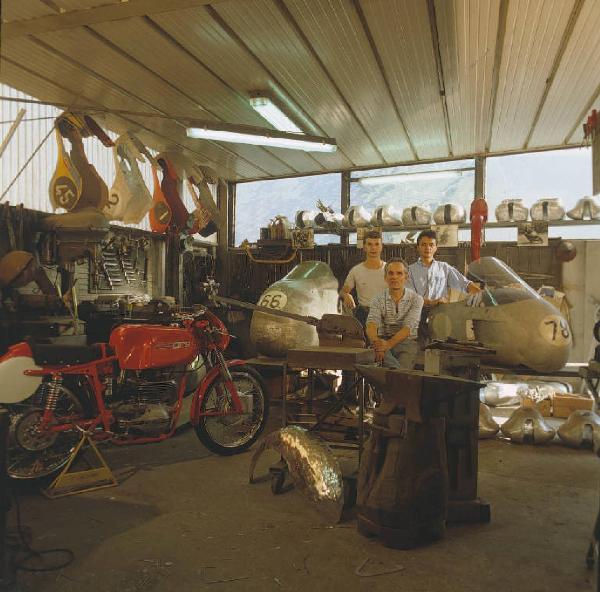 Officina di moto d'epoca - titolare e dipendenti in posa accanto ad alcune motociclette