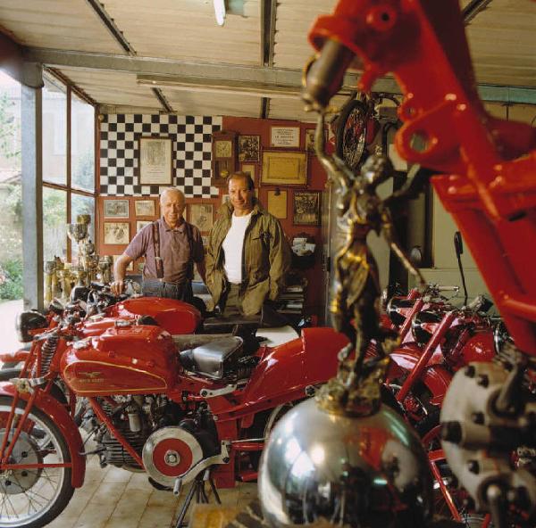 Officina di moto d'epoca - il titolare in posa tra le motociclette