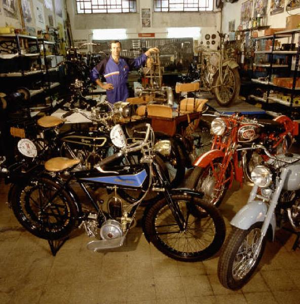 Officina di moto d'epoca - il titolare in posa tra le motociclette