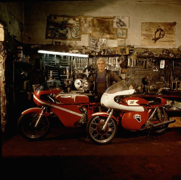 Officina di moto d'epoca - il titolare in posa tra le motociclette