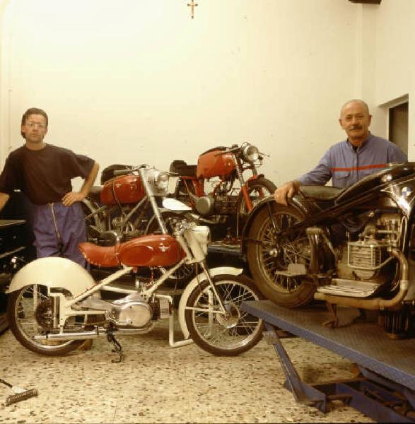 Officina di moto d'epoca - i titolari in posa tra le motociclette