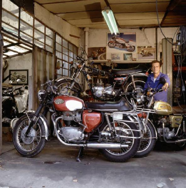 Officina di moto d'epoca - il titolare in posa tra le motociclette