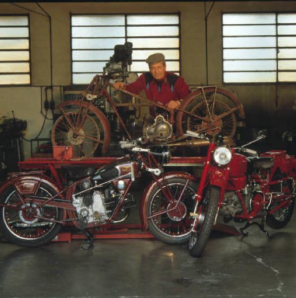 Moto officina - il titolare posa accanto ad alcune moto d'epoca