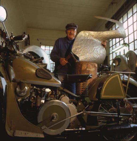 Moto officina - il titolare posa accanto a una moto d'epoca