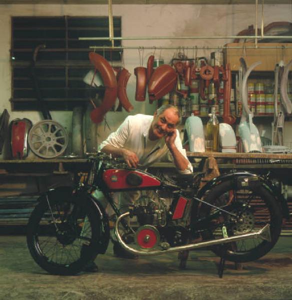 Moto officina - il titolare posa accanto a una moto d'epoca