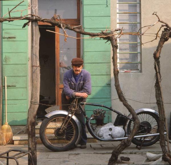 Meccanico posa accanto al telaio di una moto d'epoca nel cortile