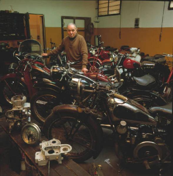 Moto officina - il titolare in posa tra le motociclette d'epoca