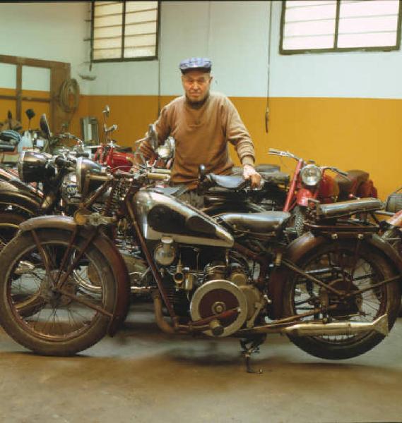 Moto officina - il titolare in posa tra le motociclette d'epoca