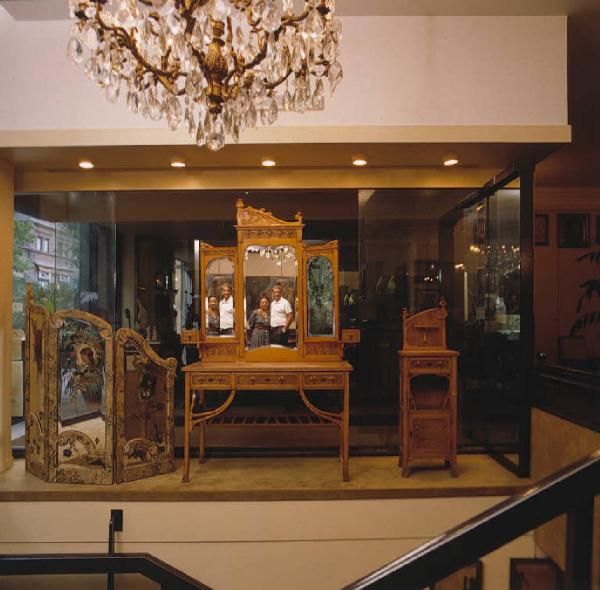 Interno di un negozio di antichità in Via dei Calderai - I titolari in posa si riflettono nello specchio di un mobile in esposizione
