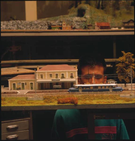 Modellismo - Particolare di bambino che osserva il plastico di una stazioneferroviaria con trenino