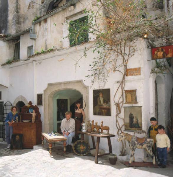 Esposizione di oggetti d'antiquariato in cortile con gruppo di donne e coppia di bambini in posa