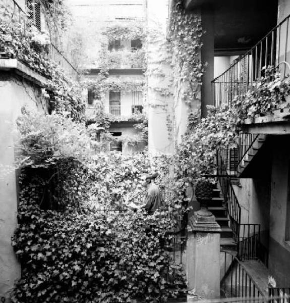 Cortile di ringhiera di Via Fiori Chiari con Tomshinsky Stanley che porta in spalla una bicicletta