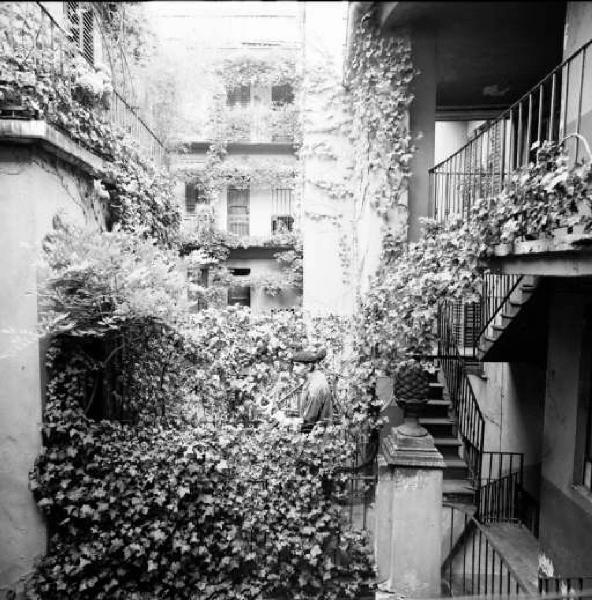 Cortile di ringhiera di Via Fiori Chiari con Tomshinsky Stanley che porta in spalla una bicicletta