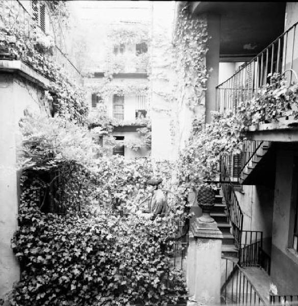 Cortile di ringhiera di Via Fiori Chiari con Tomshinsky Stanley che porta in spalla una bicicletta