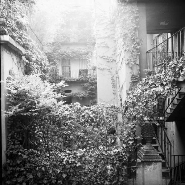 Cortile di Via Fiori Chiari con passante che trasporta un cavalletto da pittore