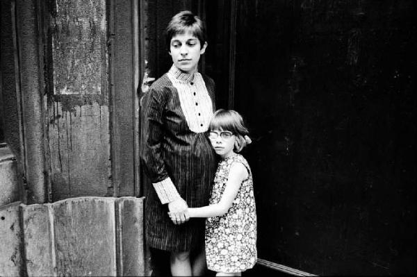 Ritratto femminile - bambina con giacca da adulto posa appoggiata a un muro - Paola Martini Salvioni, fotografa e la figlia Lorenza