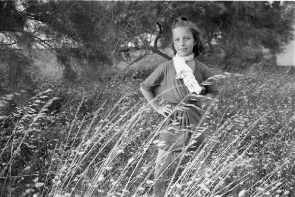 Ritratto femminile - bambina in un campo con una palla in mano