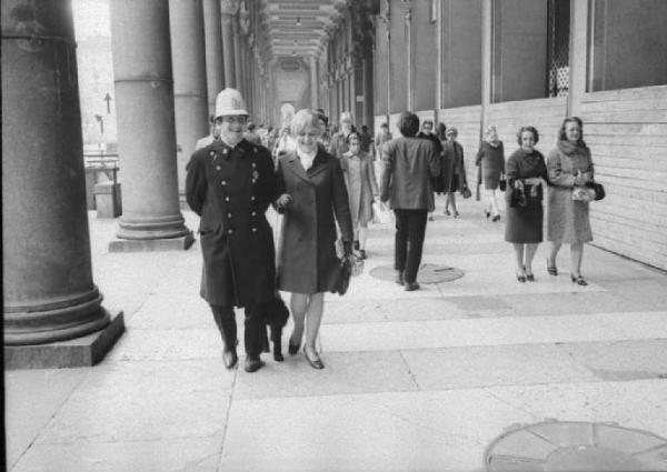 Milano - Vigile e signorina passeggiano sotto i portici di Piazza Duomo