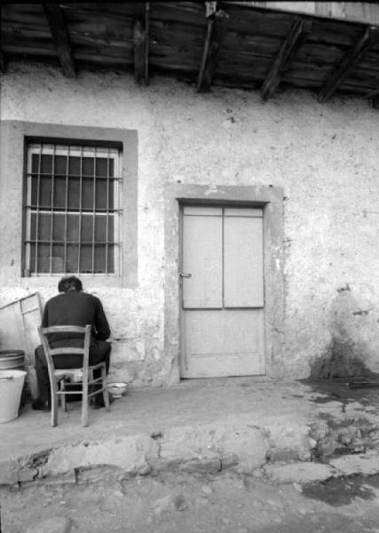 Esterno di un cascinale con uomo seduto su una sedia