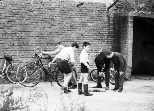 Gruppo di bambini che guarda dentro un buco del terreno