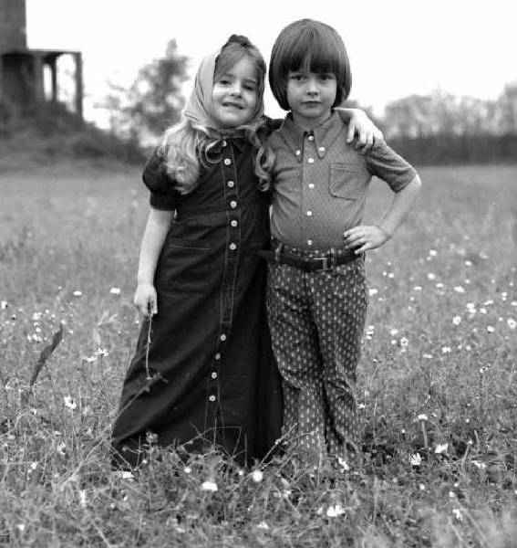 Bambino e bambina che scherzano fra loro su una strada sterrata