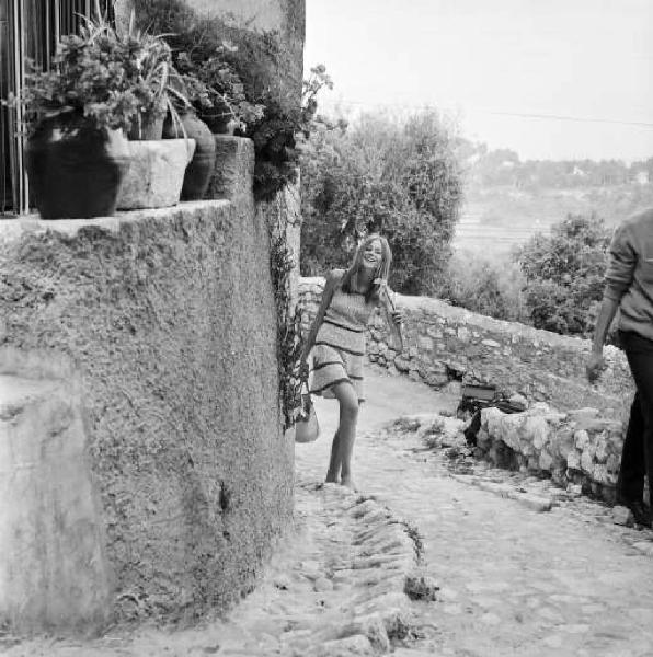 Modella cammina per i vicoli di un paese in pietra