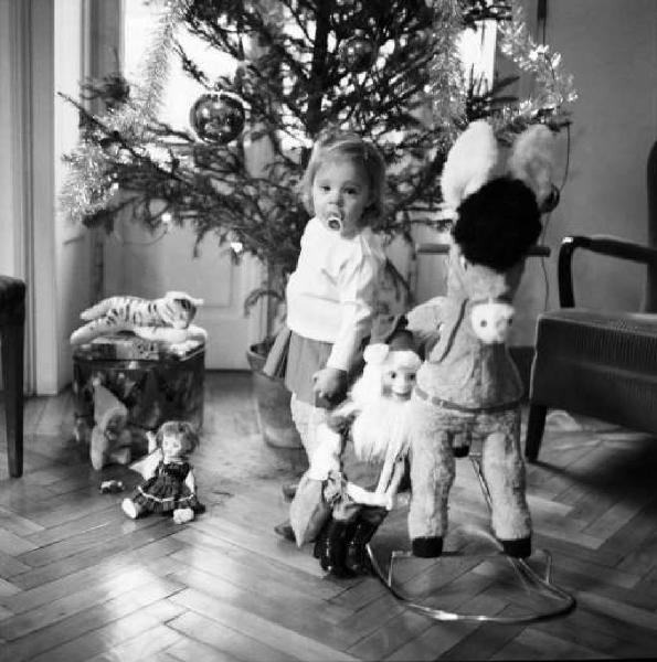 Laudie bambina con giocattoli sotto l'albero di Natale