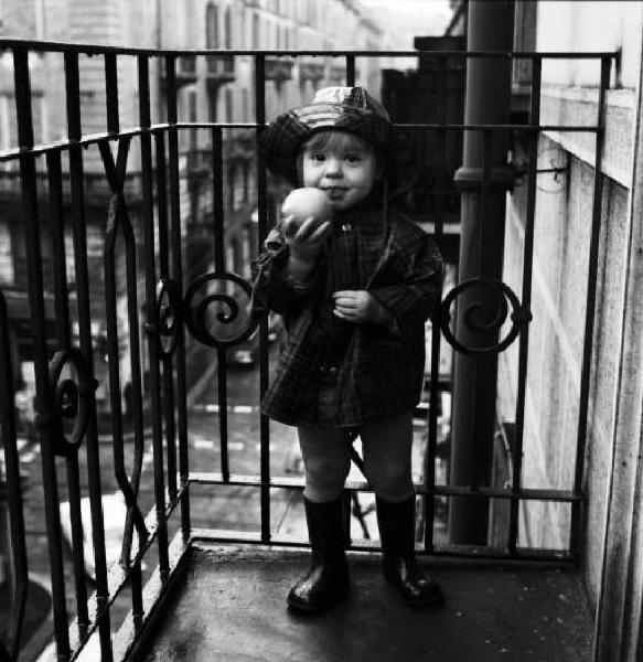 Bambina sul balcone con una mela in mano