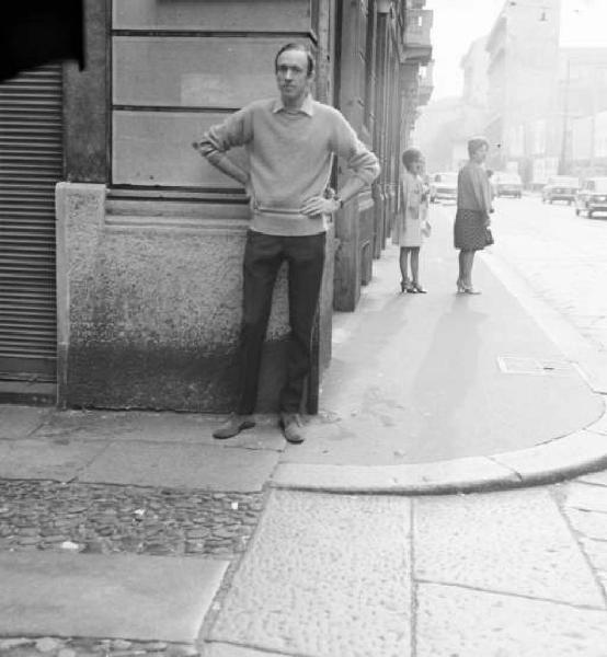 Milano - Giovane uomo con le mani sui fianchi in piedi sul marciapiede ad un angolo di strada