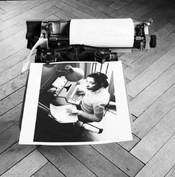 Fotografia di un'impiegata al lavoro appoggiata su di una macchina per scrivere