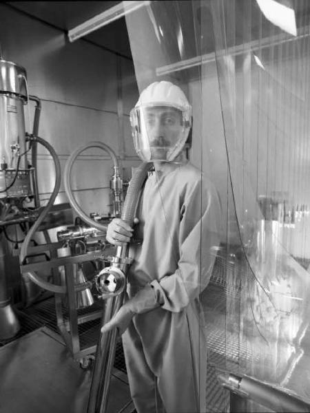 Glaxo - Ritratto di un medico con tuta, guanti e maschera protettiva - attorno le apparecchiature da laboratorio