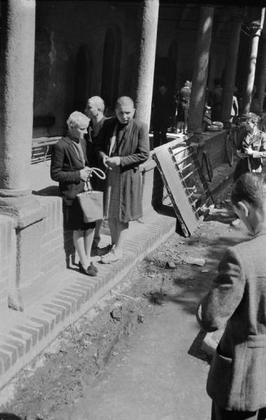 Seconda guerra mondiale. Resistenza italiana. Liberazione di Milano. 29 aprile 1945. Via San Gregorio, nel chiostro del Lazzaretto, tre donne accusate di collaborazionismo rasate a zero e sorvegliate da un partigiano armato di moschetto.