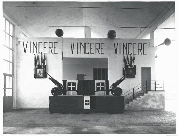 VI sezione Ernesto Breda - Brescia - Via Lunga - Stabilimento industriale - Interno - Salone allestito per cerimonia - Comizio fascista - Palco - Bandiere - Stendardi - Scritta Vincere