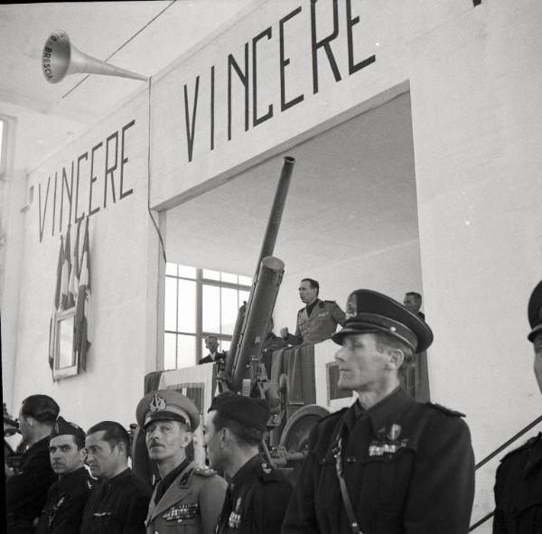 VI sezione Ernesto Breda - Brescia - Via Lunga - Stabilimento industriale - Interno - Salone allestito per cerimonia - Comizio fascista - Palco - Bandiere - Stendardi - Scritta Vincere - Gerarchi - Militari - Discorso