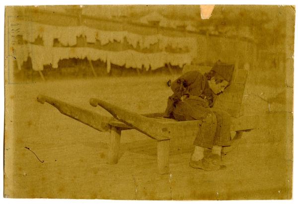 Bambino lavoratore che dorme su un carretto di legno