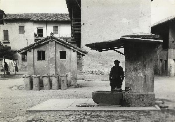 Milano - Quartiere Lampugnano - Cortile di cascina  - Un uomo riempie un secchio alla fontana
