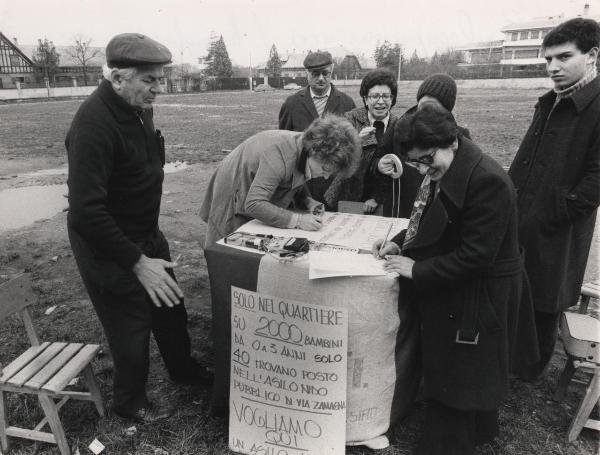 Milano - Quartiere San Siro - Via Rospigliosi - Raccolta di firme per la mancanza di asili nido - Una donna firma la petizione  - Cartello di protesta
