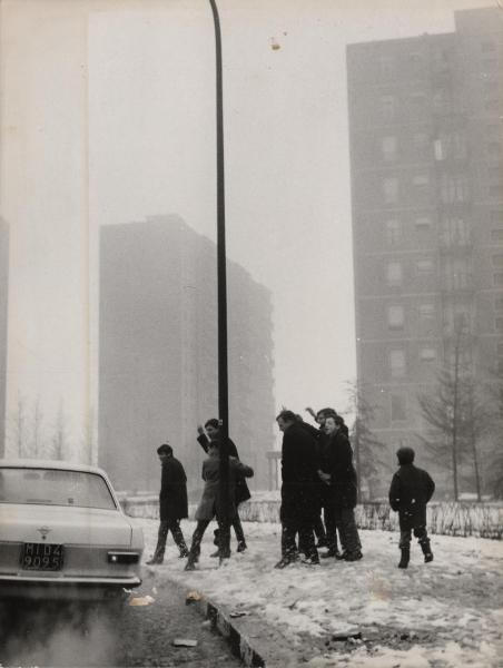 Milano - Quartiere Gratosoglio - Gruppo di ragazzi scherza sul marciapiede innevato - Sullo sfondo palazzi di edilizia popolare - Automobile passa per strada