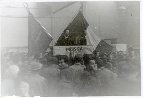 Milano - Taliedo - Fabbrica della Caproni - Francesco Scotti parla ai lavoratori su un palco addobbato con cartelli - Bandiere - Cartelli