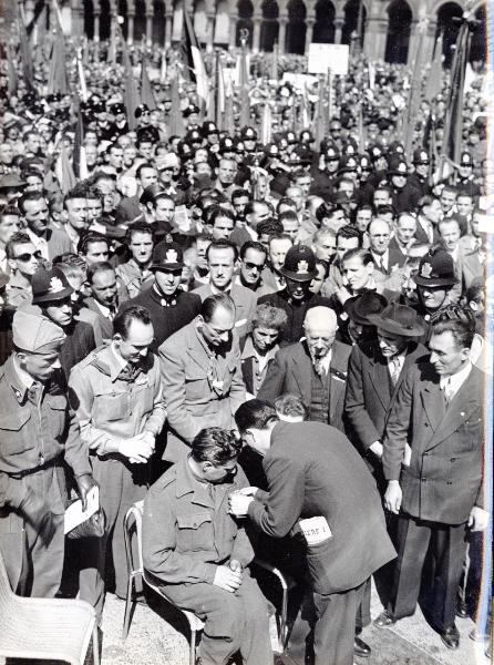 Milano - Piazza del Duomo - Festa della Liberazione - Francesco Scotti  appunta una medaglia a un partigiano invalido - Di fronte: Giovanni Pesce e Piero Montagnani - Folla - Bandiere