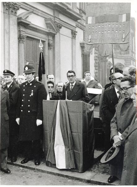 Milano - Via Marina, angolo via Senato - Facciata dell'Archivio di Stato - Funerali di Francesco Scotti - Il sindaco Aldo Aniasi al microfono - A destra, con il cappello in mano, Armando Cossutta - Bandiere - Militari